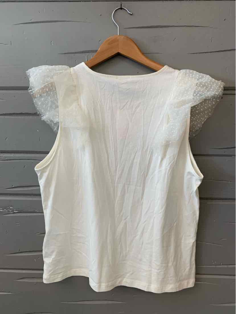 White sleeveless top with sheer lace cap sleeves on wooden hanger against gray wood wall.