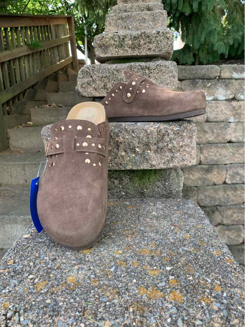 Brown suede women’s shoes with studded straps and rounded toes, displayed on stone steps.