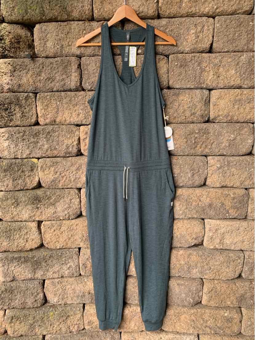 Gray sleeveless jumpsuit with deep V-neck, adjustable waist tie, and cuffed ankles hanging on wooden hanger.