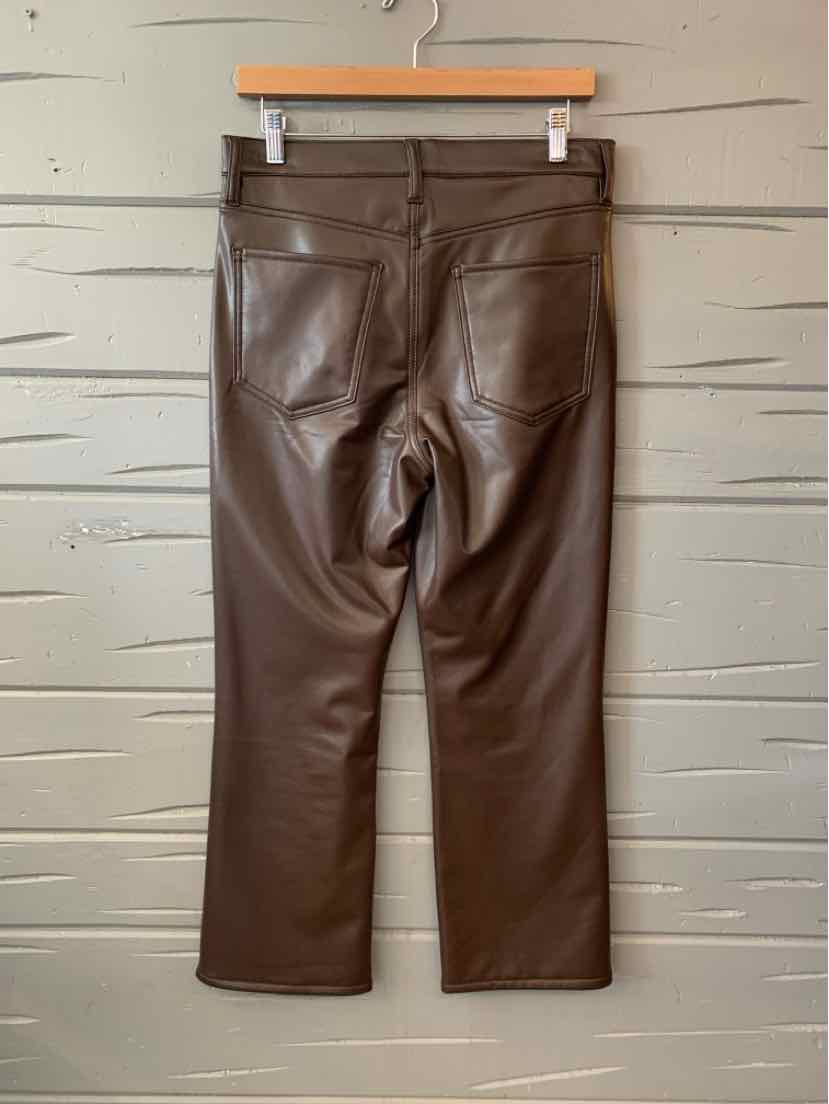 Brown leather cropped pants with back pockets and belt loops hanging on wooden hanger.