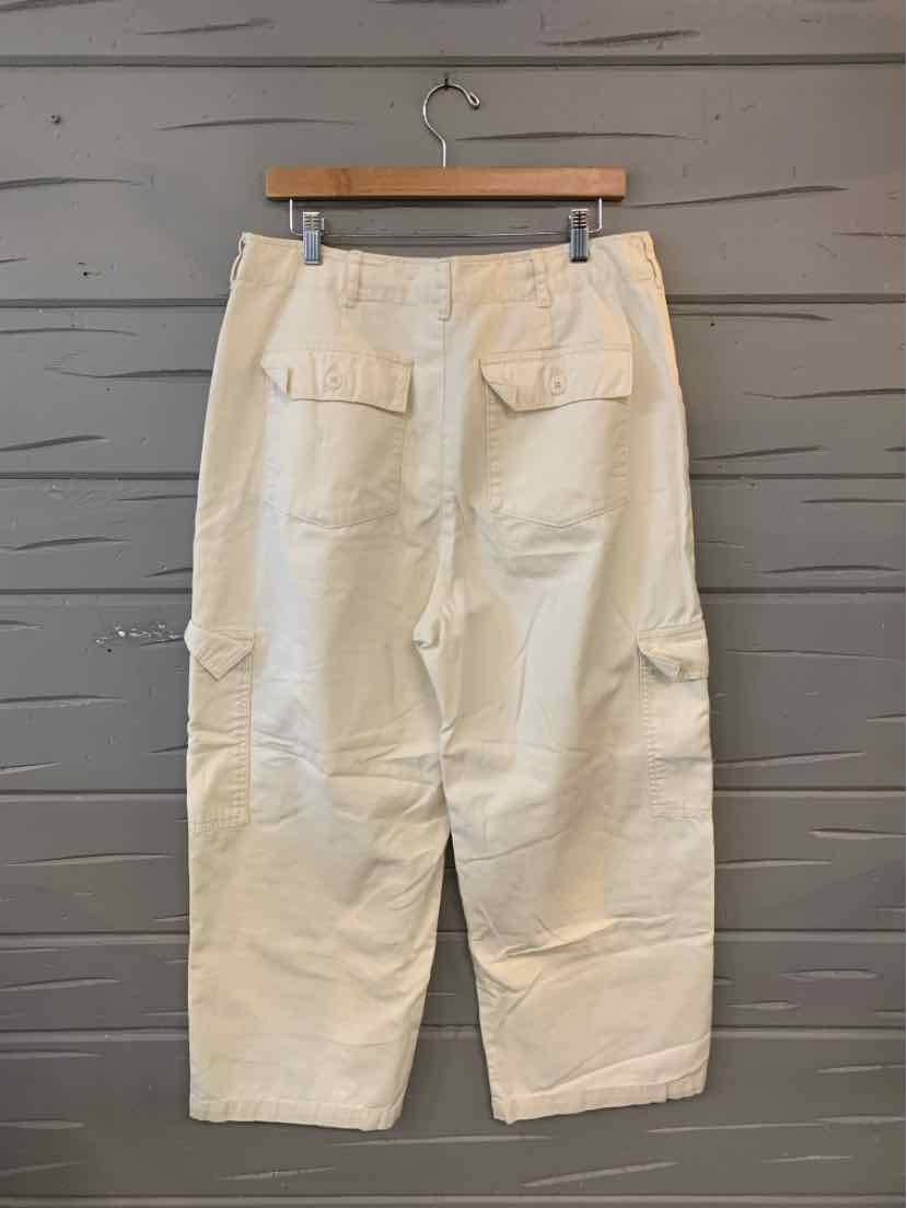 High-waist cream wide-leg pants with back flap pockets and button closures on wooden hanger.