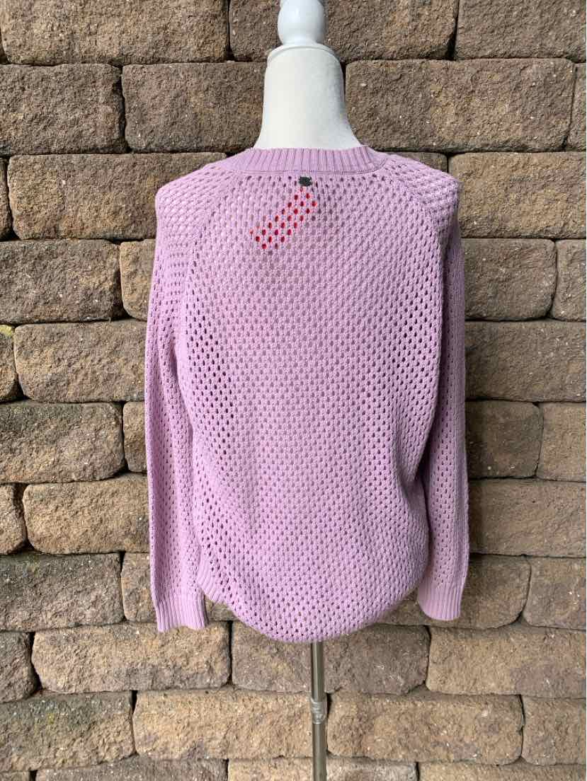 Mauve knit sweater with textured pattern and long sleeves on mannequin against stone wall.