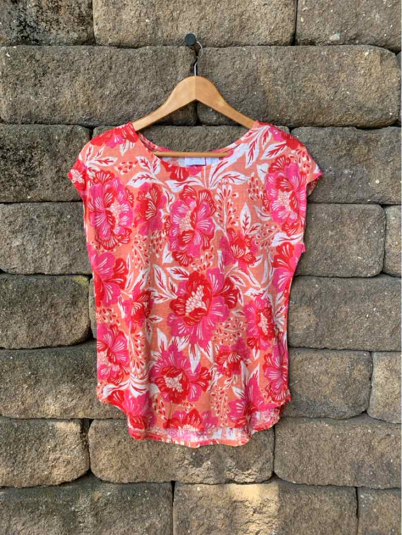 Pink floral short-sleeve blouse with round neckline and relaxed fit hanging on wooden hanger.
