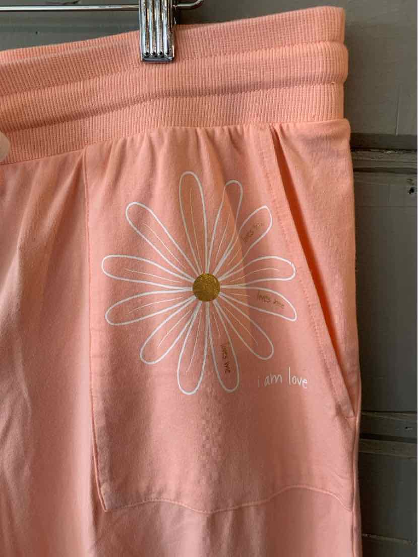 Peach-colored casual shorts with elastic waistband and white daisy graphic on left leg.