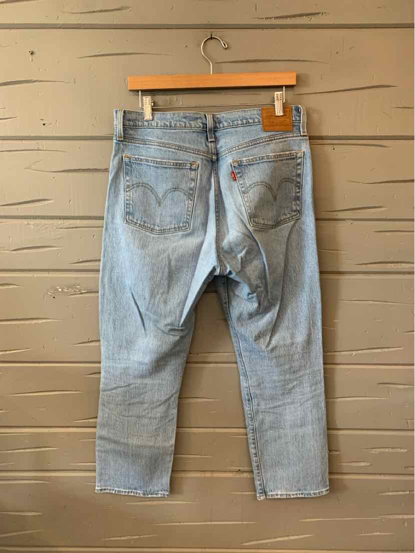 Light wash blue denim Levi’s jeans size 10 with classic back pockets and straight legs hanging on wooden hanger.
