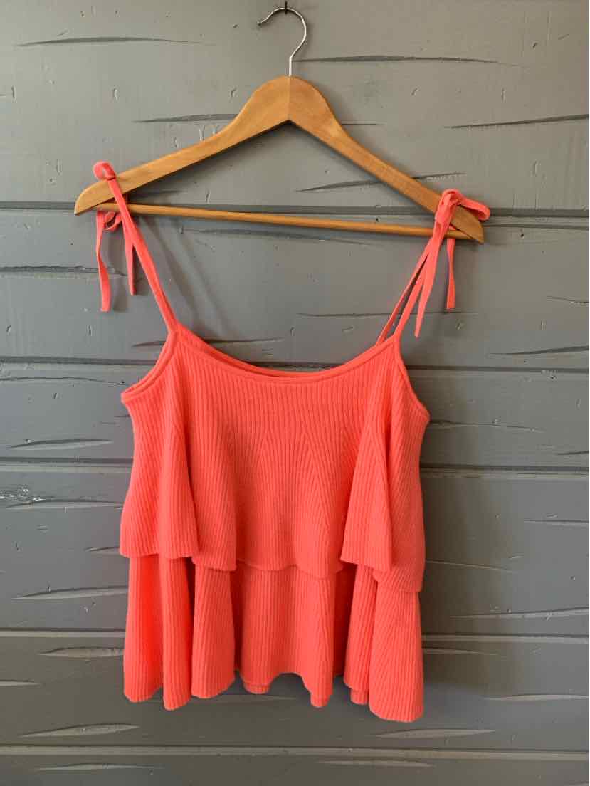 Coral pink sleeveless knit tank top with layered ruffle and tie straps on wood hanger.