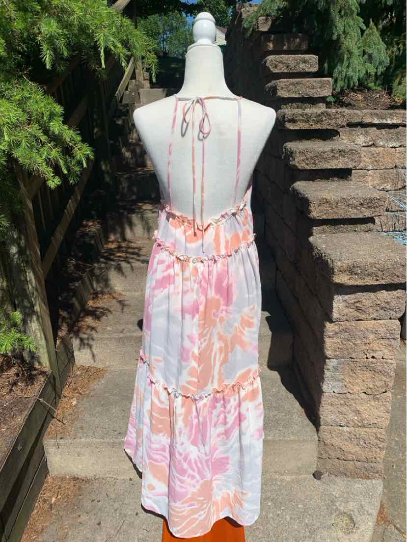 Back view of sleeveless maxi dress with pink and orange floral pattern, open back with tie straps, and tiered skirt.