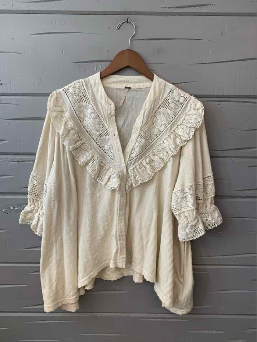 Cream-colored blouse with lace ruffle details along the front and sleeves, loose fit, size XS.