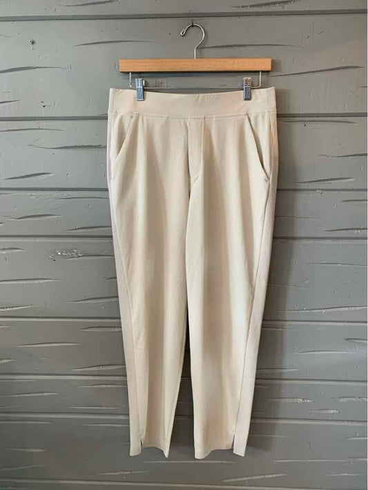 Beige tailored pants with front pleats and side pockets, slim ankle-length cut, lightweight fabric.