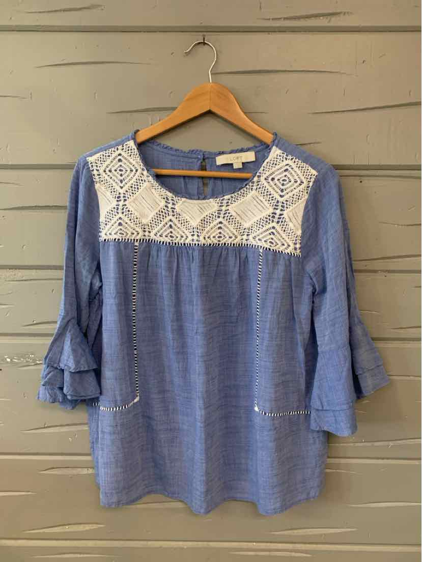 Blue blouse with 3/4 ruffled sleeves and white embroidered lace yoke on front.