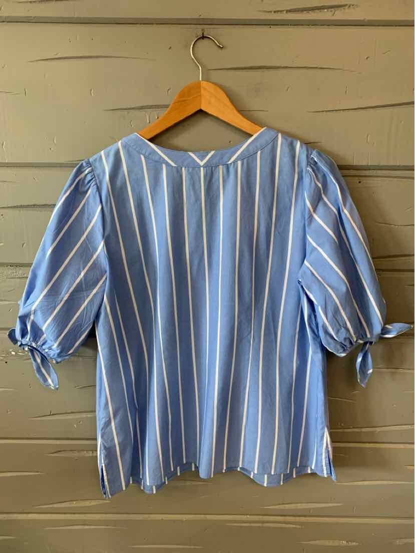 Blue blouse with white vertical stripes, puff sleeves, tie details, and V-neck on wooden hanger.