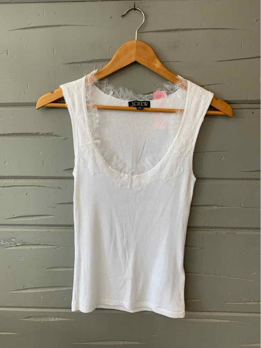 White sleeveless scoop neck tank top with scalloped trim, size XS on wooden hanger against gray background.