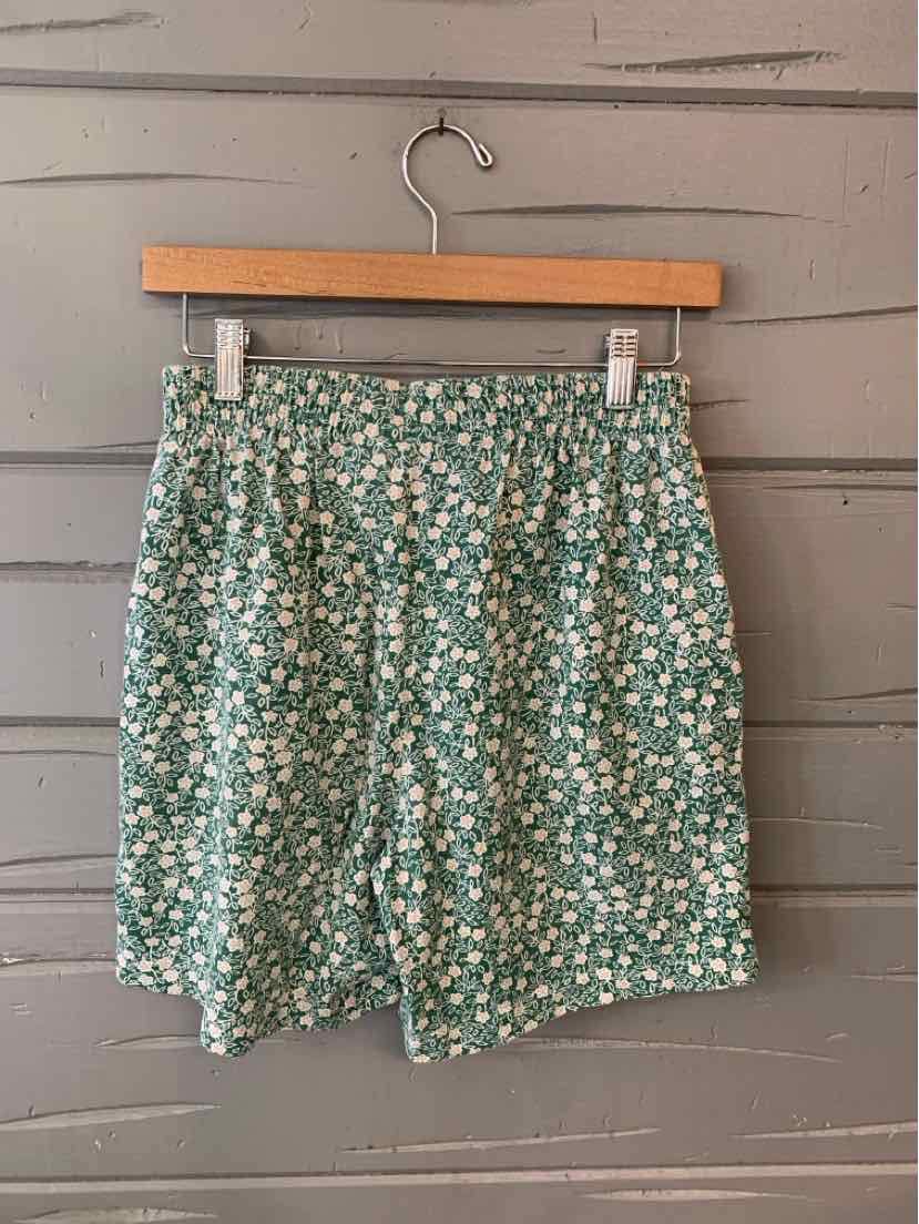 Green floral high-waist shorts with white and yellow flower print and elastic waistband.