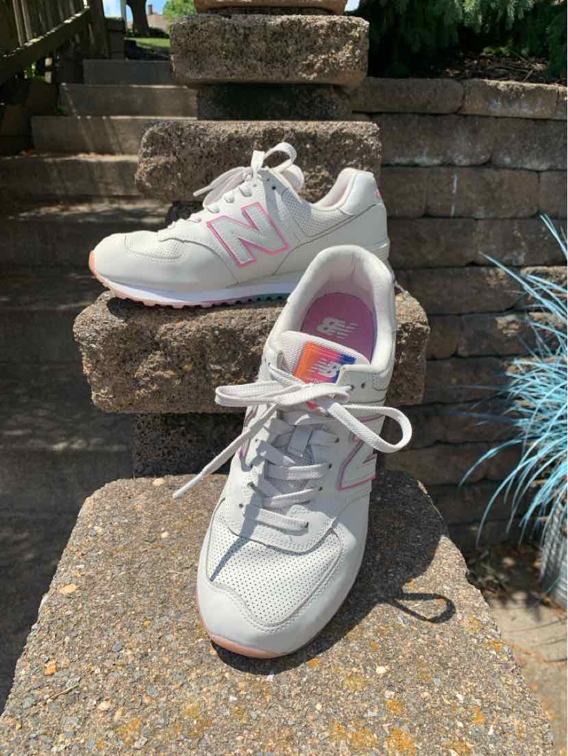 Light gray New Balance sneakers with pink "N" logo, white laces, and cushioned soles, size 9.