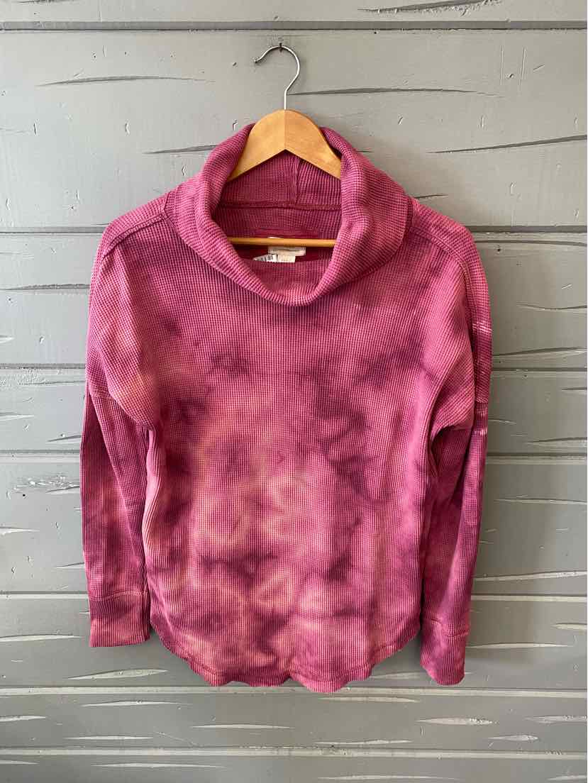 Pink tie-dyed long-sleeve turtleneck sweater with relaxed fit on wooden hanger.