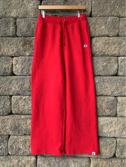 Red wide-leg fleece sweatpants with drawstring waist and small Champion logo patches.