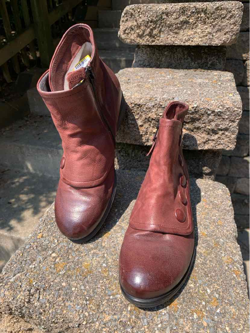 Burgundy leather ankle boots with rounded toes, side zippers, and slight creasing on the shaft.