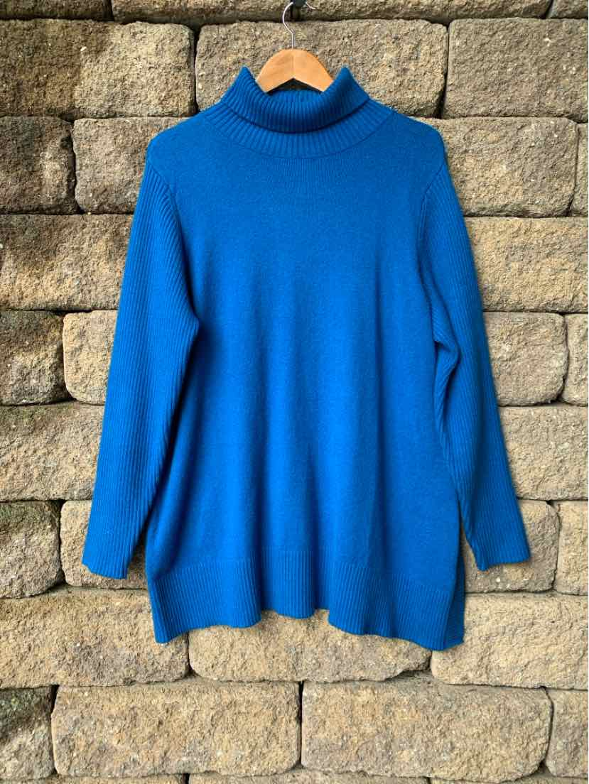 Blue knit turtleneck sweater with long sleeves in a relaxed fit, hanging on a wooden hanger.