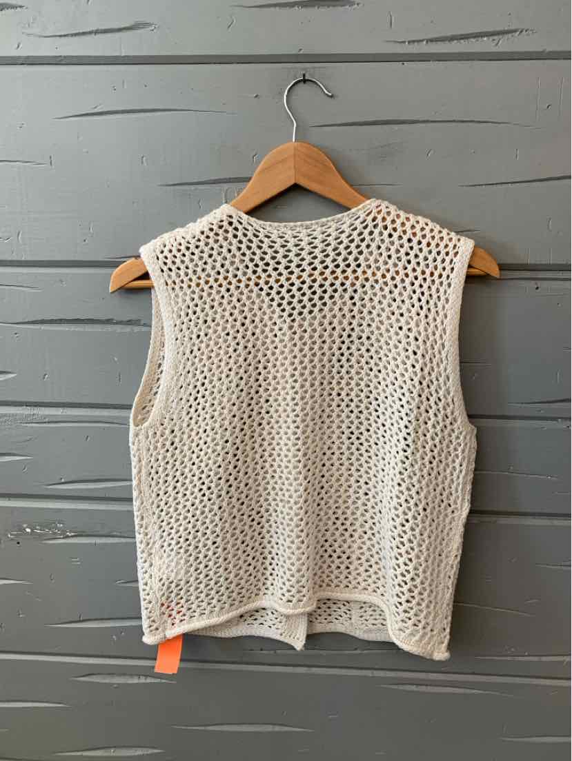 White open-knit sleeveless sweater vest with loose weave, hanging on wooden hanger.