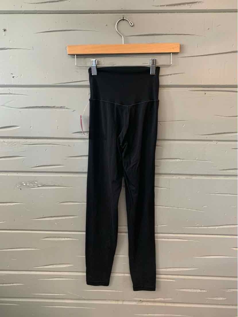 Black high-waisted leggings with a fitted silhouette, ribbed waistband, and ankle cuffs, hanging on a wooden hanger.