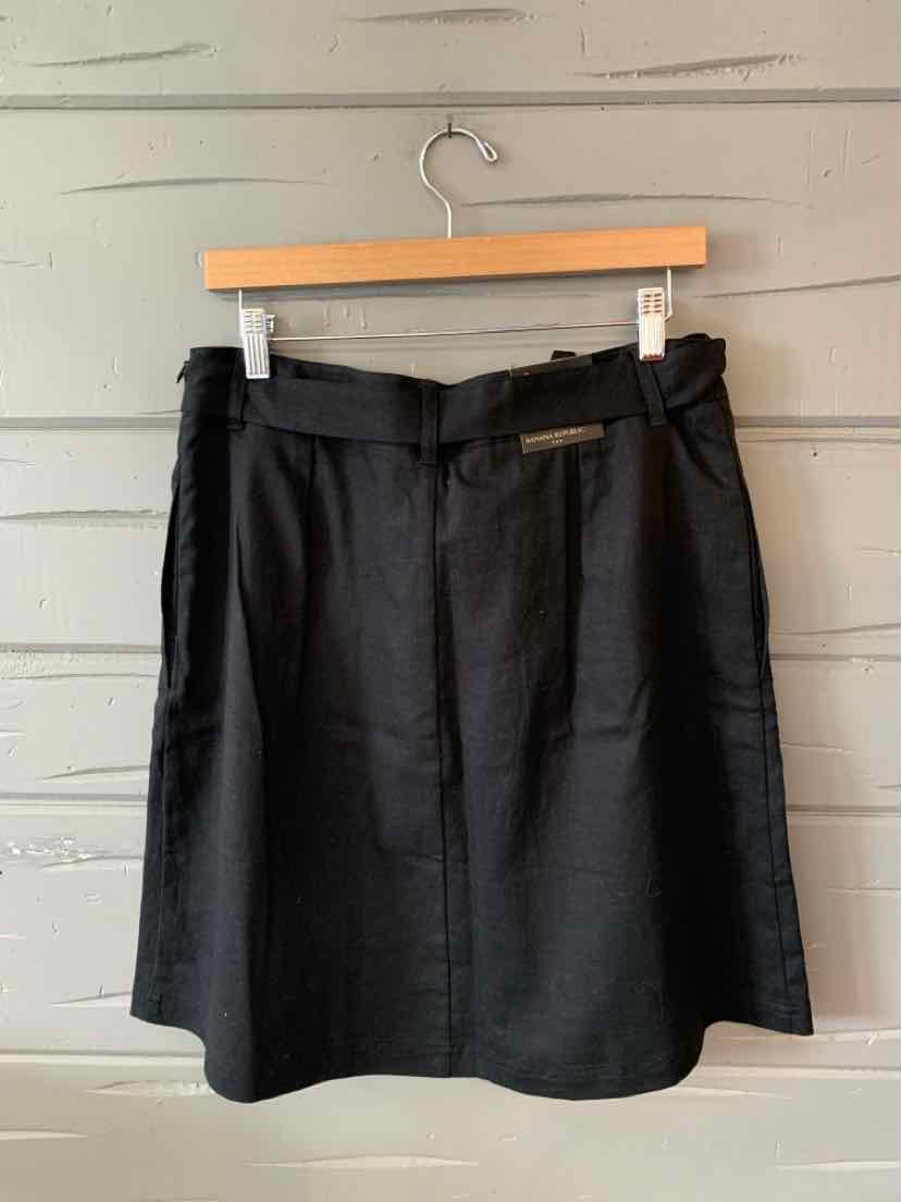 Black knee-length skirt with front pockets and a matching fabric belt, size 12.