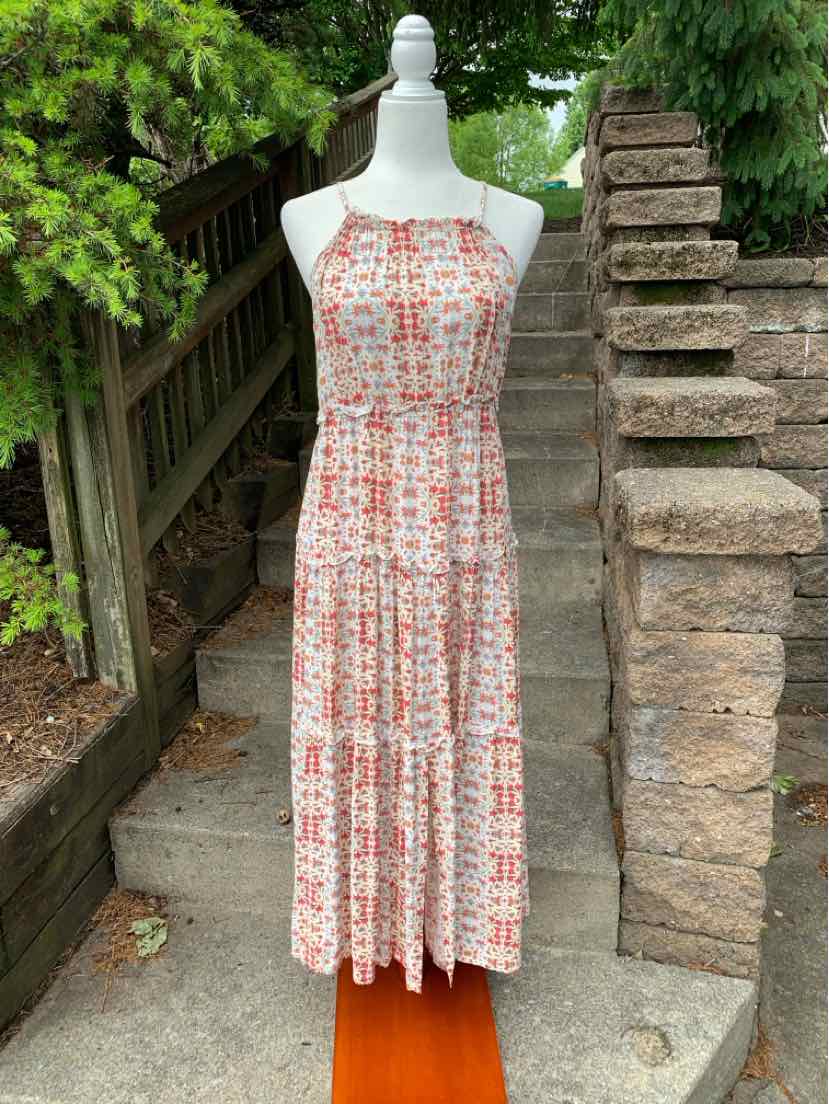 Sleeveless pink floral midi dress with gathered waist and thin shoulder straps on mannequin outdoors.