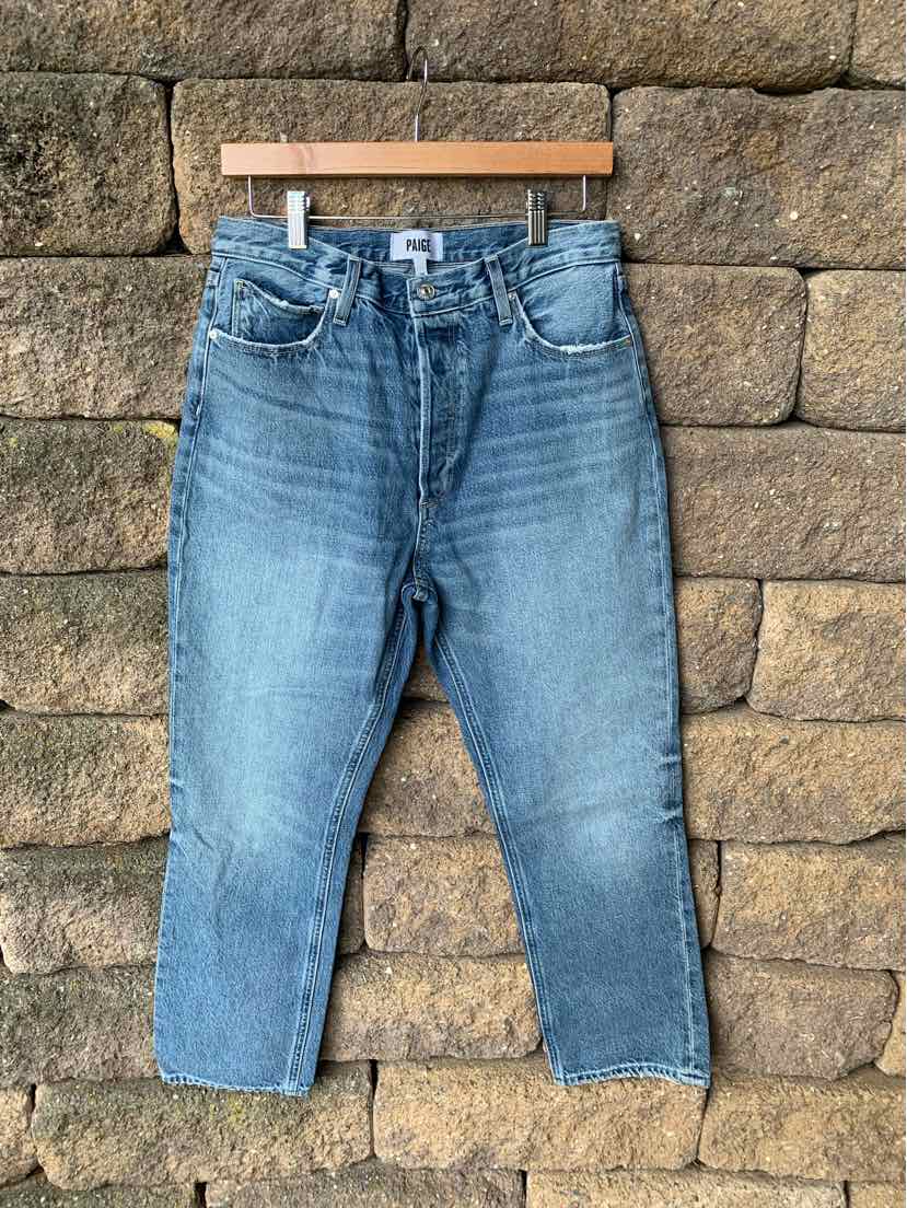 Blue high-waisted straight-leg jeans with front button and zipper closure hanging on wooden hanger.