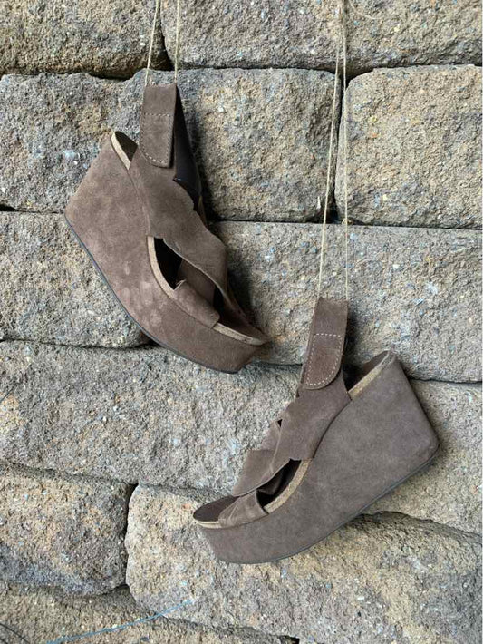 Brown suede wedge sandals with cutout sides and adjustable ankle straps.