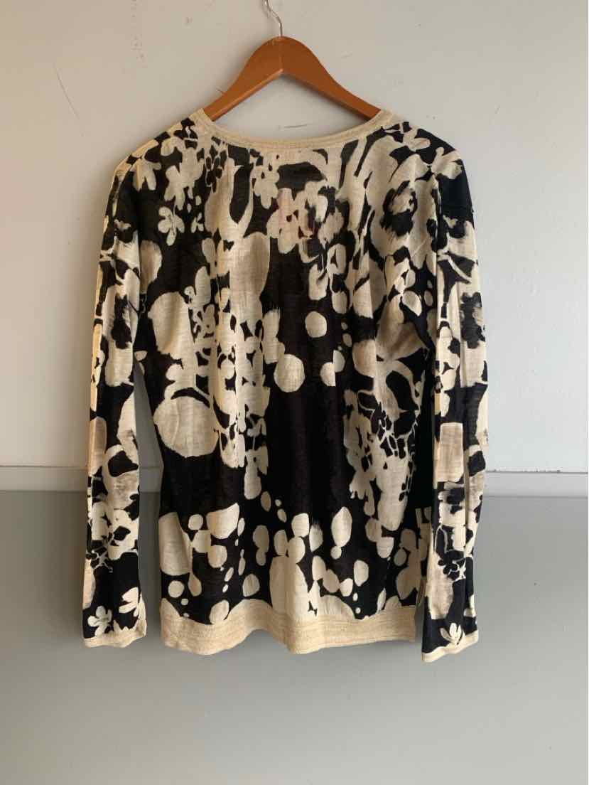 Black and white floral long-sleeve blouse with round neckline hanging on wooden hanger.