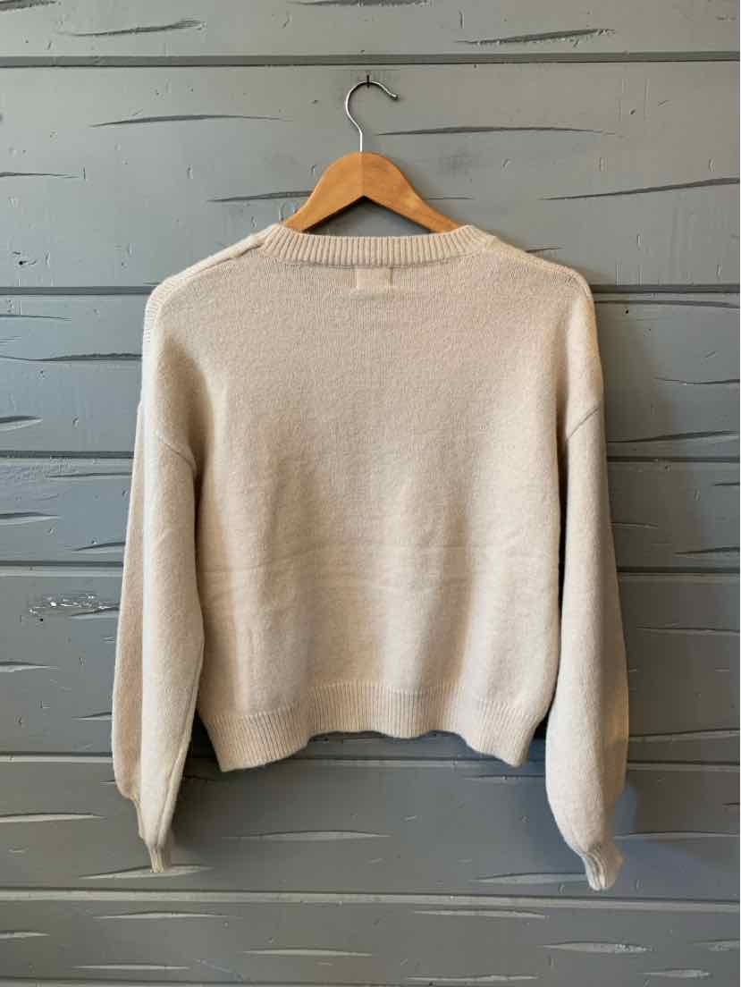 Light beige knit sweater with a crew neck, long sleeves, and a relaxed cropped hem.