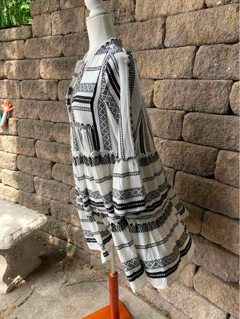 Black and white patterned tiered dress with long puff sleeves and round neckline on mannequin.