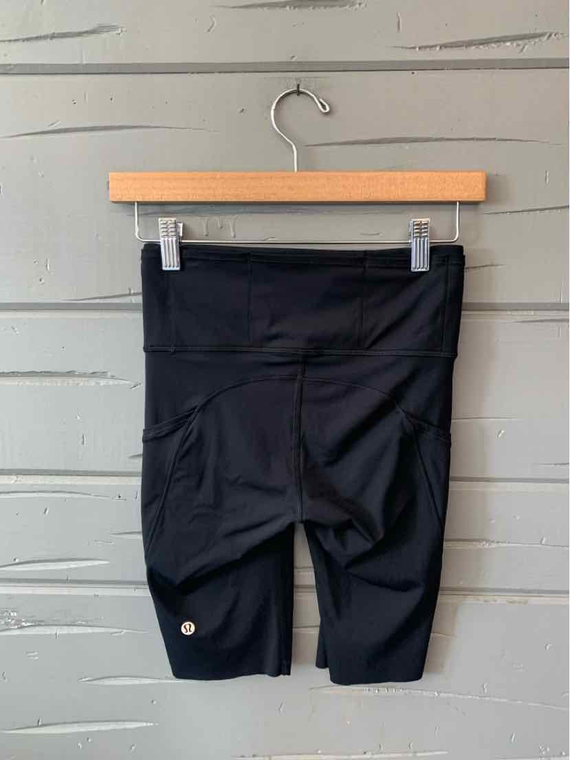 Black high-waisted athletic shorts with flat seams and a small reflective logo near the hem.