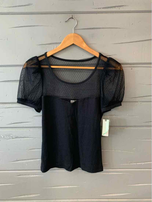 Black short-sleeve top with sheer lace yoke and sleeves on wooden hanger.