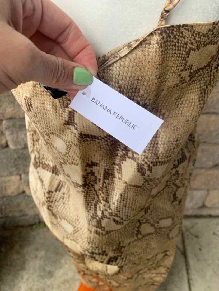 Beige and brown snake print fabric bag with Banana Republic label held by hand with green-painted nails.