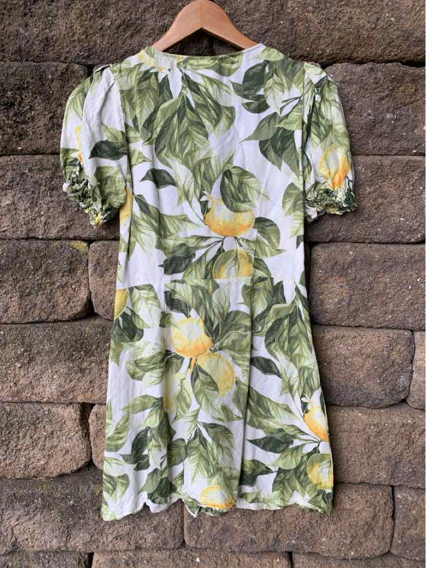 White mini dress with green leafy and lemon print, puff short sleeves, fitted waist.