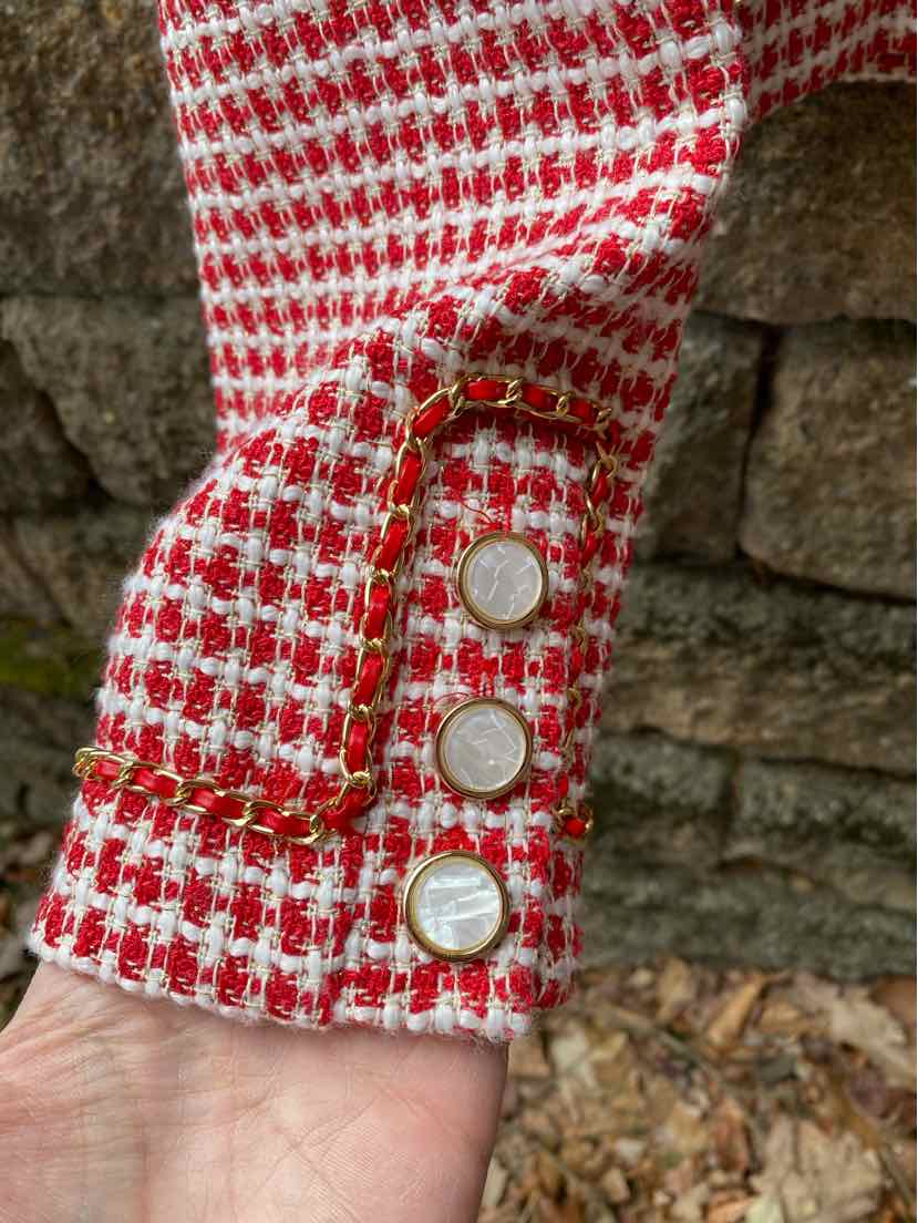 Red and white tweed blazer sleeve with gold-trimmed cuff and three white buttons.