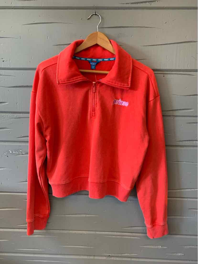 Red quarter-zip fleece pullover with stand collar and long sleeves hanging on wooden hanger against gray wall.