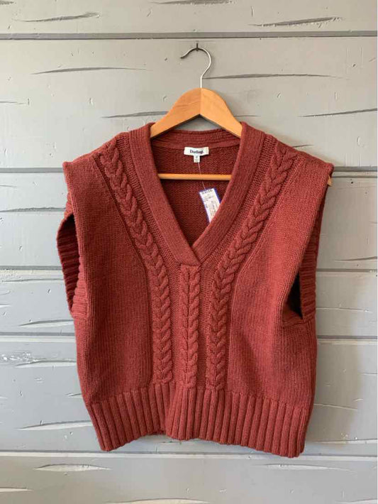 Rust-red knitted V-neck sweater vest with cable-knit details and ribbed hem, hanging on a wooden hanger.