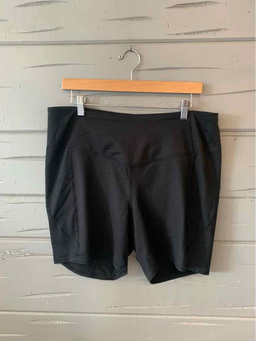 Black knee-length shorts with a straight fit and side pockets hanging on a wooden hanger.