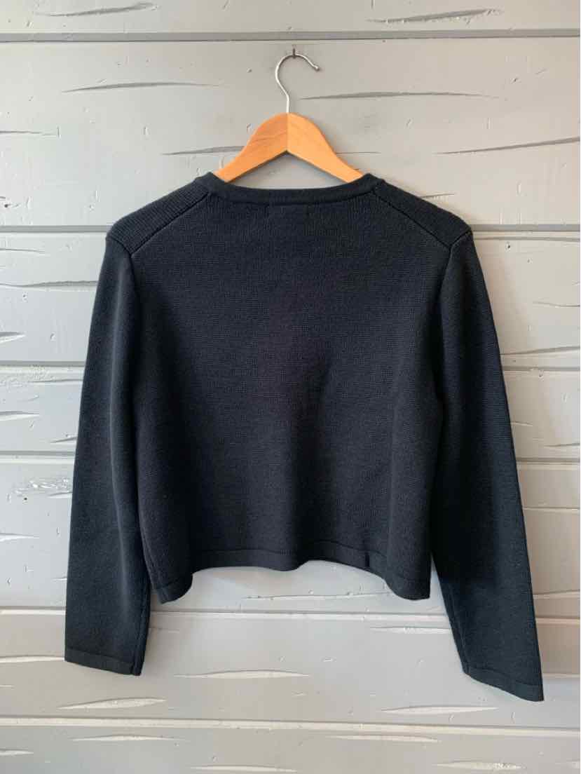 Black long-sleeve knit sweater with crew neck and fitted silhouette hanging on wooden hanger.
