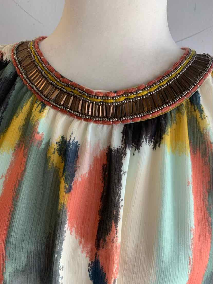 Multicolor watercolor-patterned fabric top with round neckline featuring rows of brown, pink, and gold beaded embellishments.