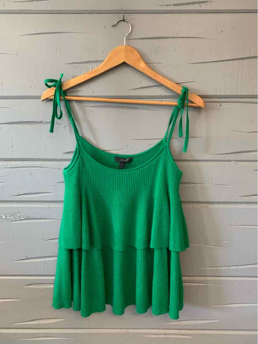 Green sleeveless knit top with tiered layers and adjustable tie straps on wooden hanger.