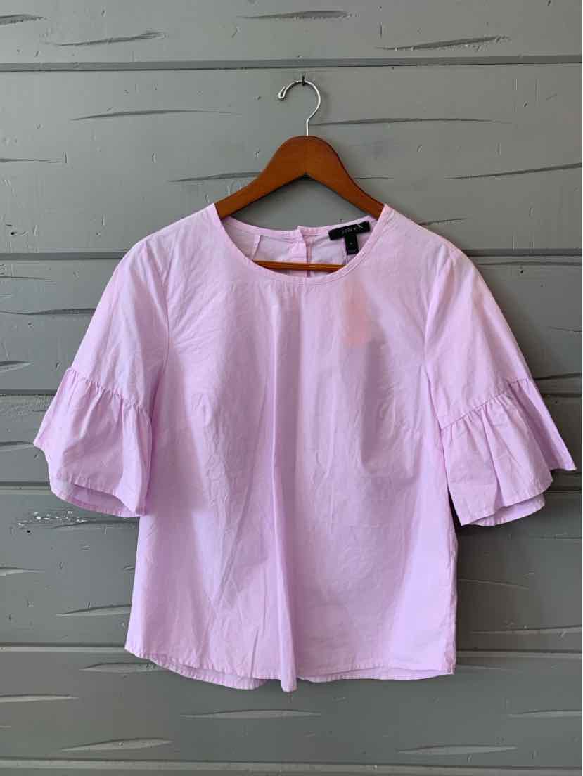 Light pink blouse with round neckline and puffed three-quarter sleeves on wooden hanger.