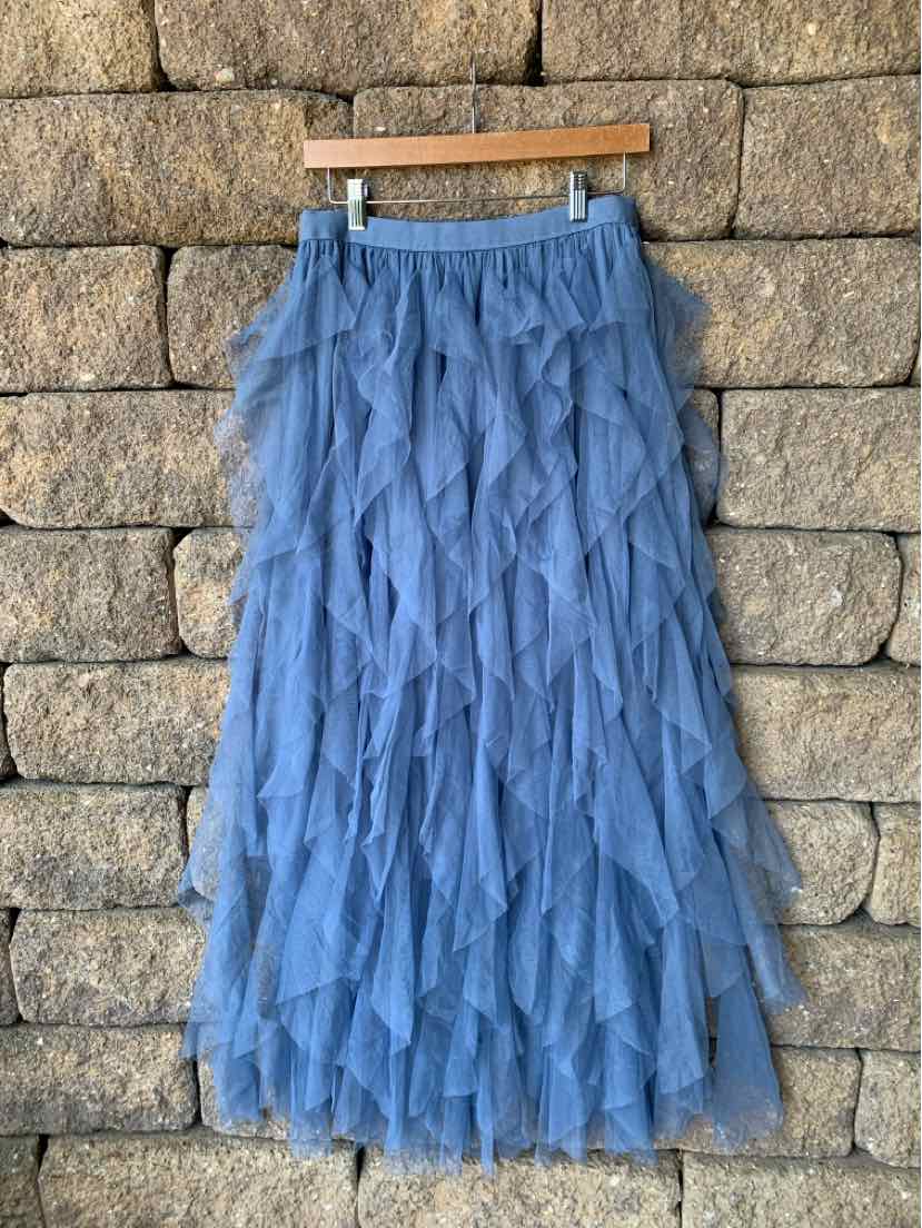 Blue tiered ruffle maxi skirt with elastic waistband in size XL hanging against stone wall.