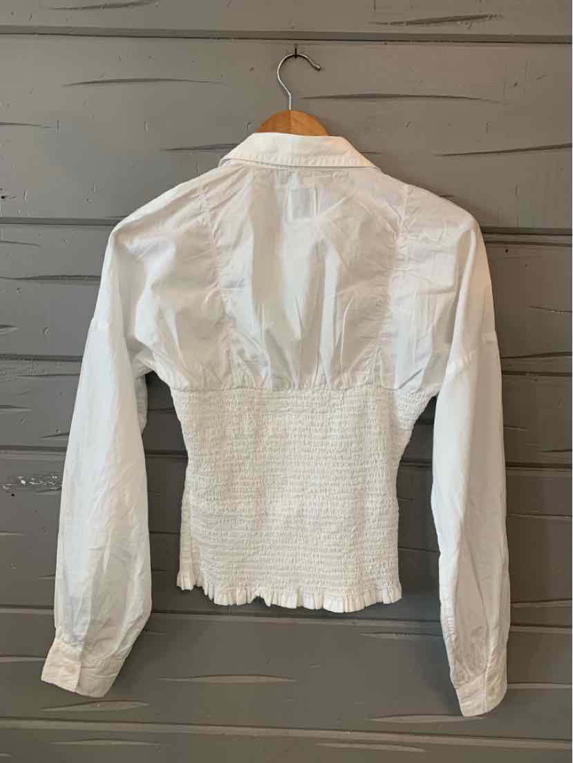 White long-sleeve blouse with shirred waist and buttoned cuffs on wooden hanger.