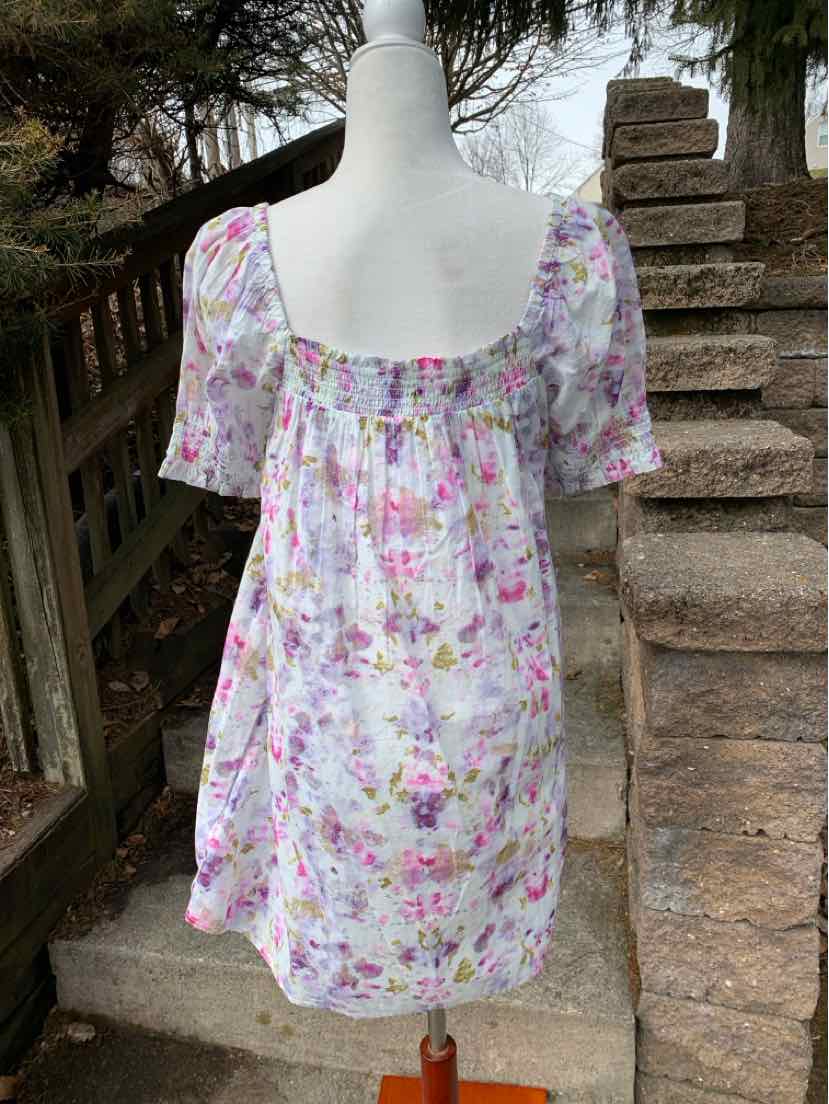 Woman’s short floral dress in pastel colors with puff sleeves and square neckline.
