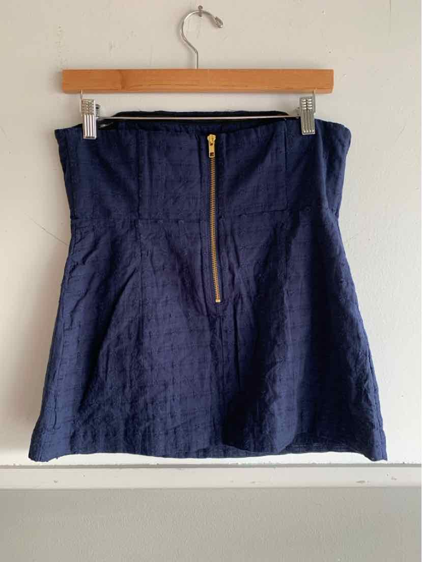 Navy blue textured skirt with front gold zipper and slightly flared hem hanging on wooden hanger.