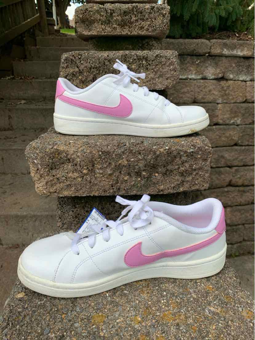 White leather Nike sneakers with pink swooshes, pale pink lining, white laces, and thick soles.