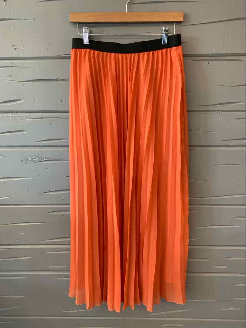 Orange pleated midi skirt with black elastic waistband hanging on wooden hanger.