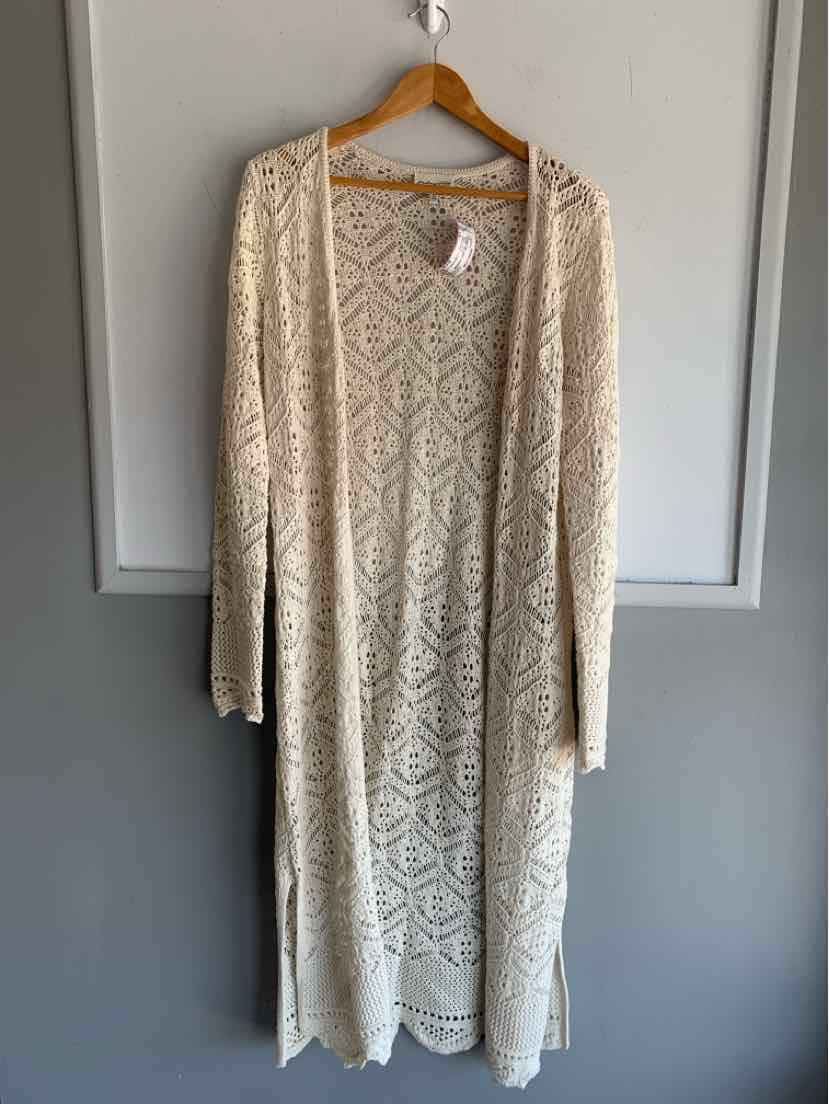 Long cream-colored knit cardigan with intricate lace-like pattern, open front, and scalloped hem detailing.